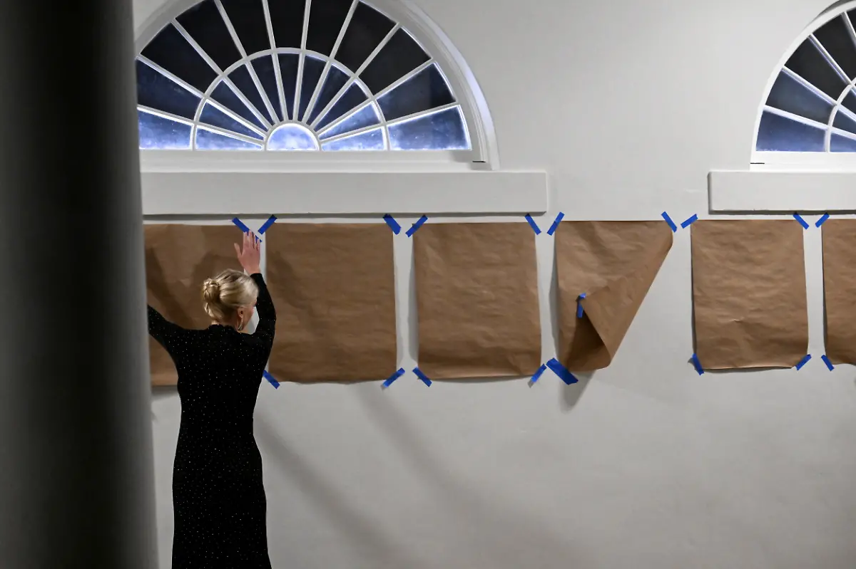 White-House-Aide-Natalie-Harp-fixes-brown-papers-pasted-below-the-writing-Presidental-Walk-of-Fame-on-the-wall-next-to-the-Rose-Garden-after-arriving-with-President-Donald-Trump-at-the-White-House-on-Marine-One-in-Washington-D-C-U-S-September-20-2025