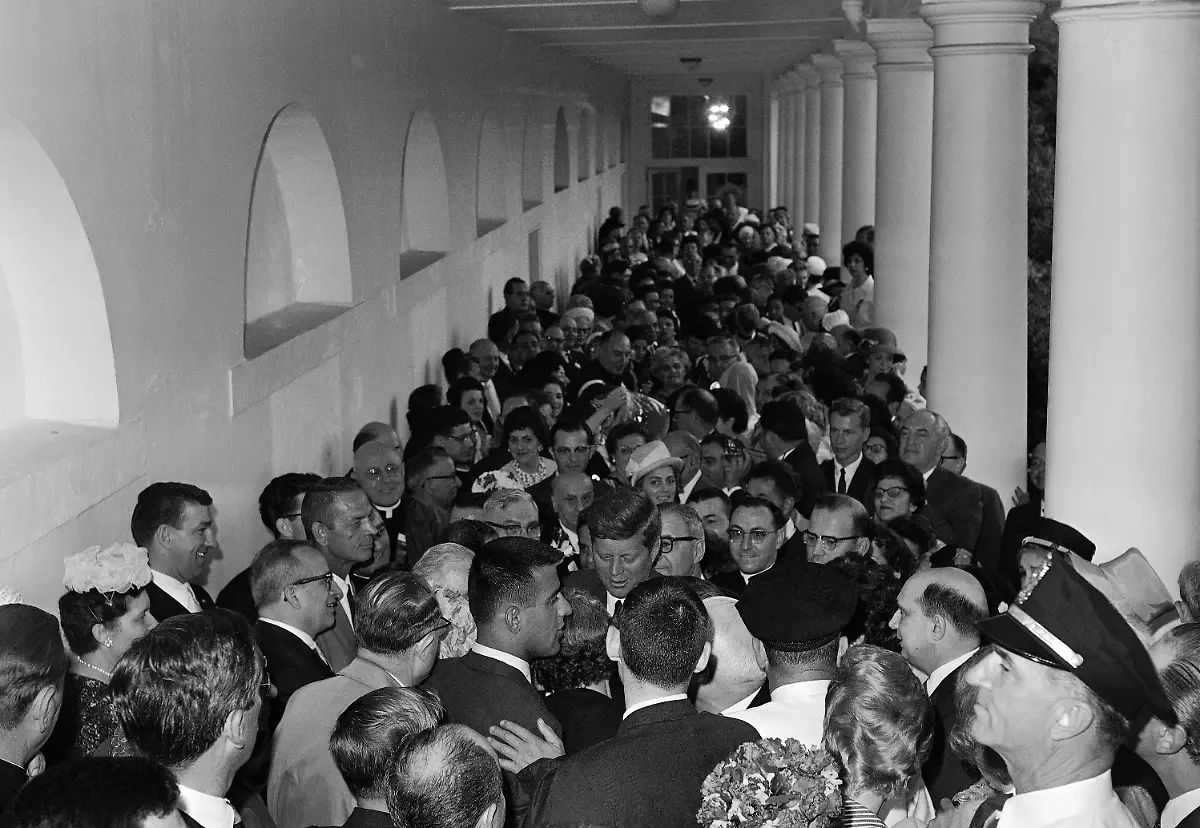 President-John-Kennedy-is-completely-surrounded-June-11-1963-as-he-mingles-with-some-200-callers-at-the-White-House-delegates-to-the-third-symposium-of-the-American-Committee-on-Italian-Migration-Rain-forced-the-gathering-into-a-long-narrow-colonnade-near-the-Rose-Garden-The-President-told-them-he-plans-to-send-Congress-next-week-a-proposal-to