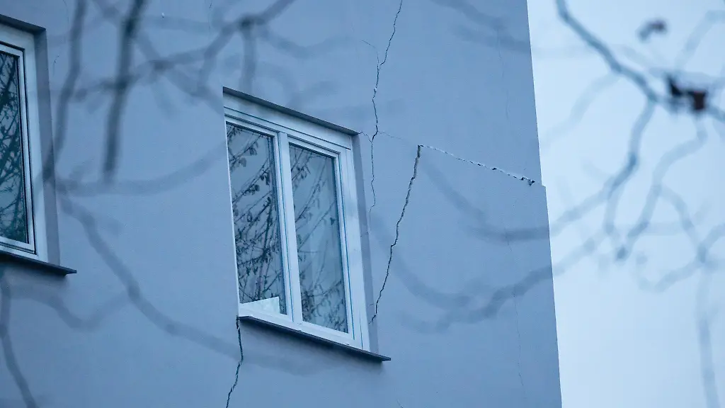 Risse-sind-an-der-Fassade-eines-Mehrfamilienhauses-zu-sehen-Weil-an-mehreren-Stellen-der-Boden-abgesackt-ist-ist-das-zweistoeckige-Haus-einsturzgefaehrdet