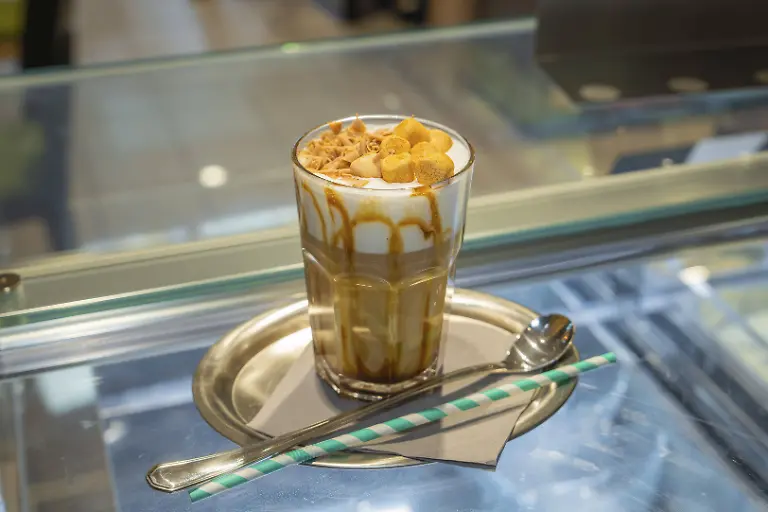 Ein-Glas-Eiskaffee-mit-Sahne-und-Karamell-auf-einem-Tablett-mit-Strohhalm-und-Loeffel-Herbstkreationen-Cafe-Kuh-Deckenpfronn-Schwarzwald-Deutschland-Europa-OrigBildgroesse-8660x5773-px