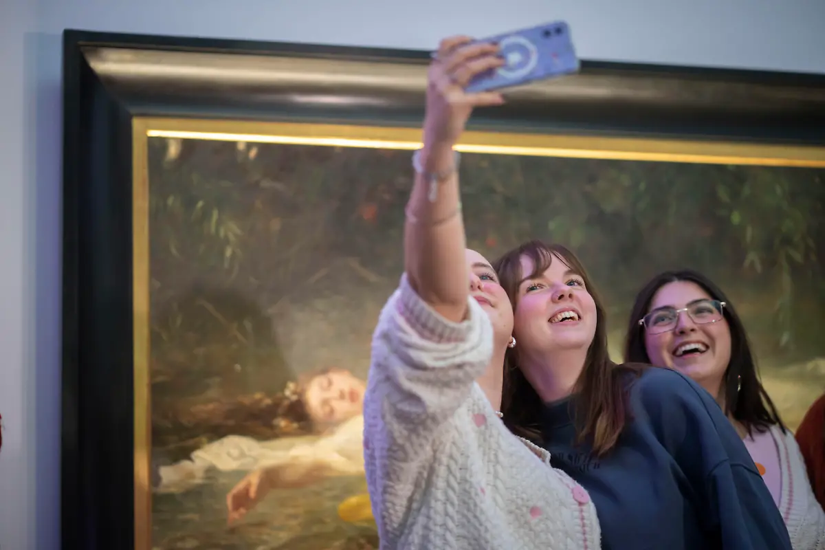 Besucherinnen-fotografieren-sich-am-Sonntag-02-11-2025-vor-dem-Ophelia-Gemaelde-im-Landesmuseum-Wiesbaden-Bei-diesem-Besuch-bekamen-diejenigen-freien-Eintritt-die-sich-als-Ophelia-oder-Taylor-Swift-verkleidet-haben-Weil-das-Ophelia-Gemaelde-von-Friedrich-Wilhelm-Theodor-Heyser-1857-1921-in-einem-Anfang-Oktober-veroeffentlichten-Musikvideo-zum-Song-The-Fate-of-Ophelia-der-Saengerin-Tayler-Swift-nachgestellt-wurde-erlebt-das-Landesmuseum-Wiesbaden-seit-Wochen-einen-Besucheransturm-Siehe-epd-Meldung-vom-02-11