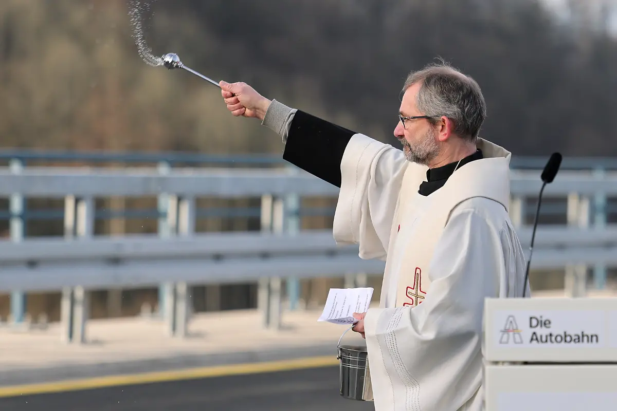 Ein-Vertreter-der-Kirche-segnet-die-Bruecke-bei-der-Eroeffnung-der-Rahmedetalbruecke-Fast-vier-Jahren-war-im-Sauerland-die-wichtige-Nord-Sued-Achse-A45-wegen-einer-maroden-Bruecke-unterbrochen-Die-marode-Bruecke-war-Anfang-Dezember-2021-gesperrt-und-spaeter-gesprengt-worden