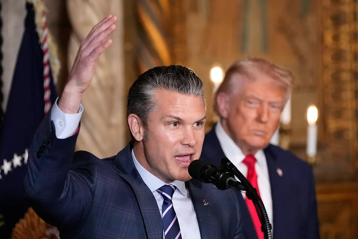 Defense-Secretary-Pete-Hegseth-speaks-as-President-Donald-Trump-looks-on-at-Trump-s-Mar-a-Lago-club-Monday-Dec-22-2025-in-Palm-Beach-Fla