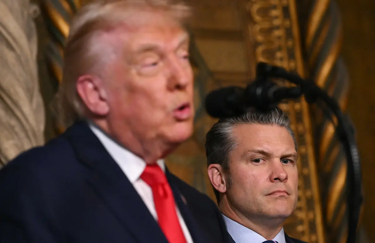 US-Secretary-of-Defense-Pete-Hegseth-R-listens-to-US-President-Donald-Trump-announcing-the-US-Navys-new-Golden-Fleet-initiative-unveiling-a-new-class-of-warships-at-Mar-a-Lago-in-Palm-Beach-Florida-on-December-22-2025-President-Donald-Trump-on-December-22-announced-a-new-class-of-heavily-armed-warships-that-will-be-named-after-himself-an-honor-usually-reserved-for-US-leaders-who-have-left-office-Two-of-the-Trump-class-ships-will-be-built-initially-but-that-number-could-grow-substantially-in-the-future-according-to-the-president-who-said-they-will-be-some-of-the-most-lethal-surface-warfare-ships-and-the-largest-battleship-in-the-history-of-our-country-Trump-made-the-announcement-at-his-Mar-a-Lago-residence-in-Florida-alongside-Pentagon-chief-Pete-Hegseth-Secretary-of-State-Marco-Rubio-and-Navy-Secretary-John-Phelan-with-images-of-the-planned-high-tech-vessels-on-stands-nearby