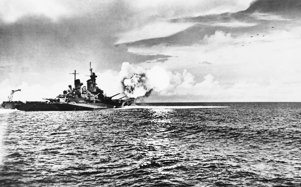 The-Missouri-one-of-the-U-S-Navys-newest-Iowa-class-battleships-lets-loose-a-salvo-from-her-forward-guns-on-Nov-24-1944-These-16-inch-projectiles-can-be-seen-in-flight-at-the-upper-right-of-the-picture-while-the-force-on-the-blast-churns-the-sea-and-flames-from-the-burning-gasses-light-a-path-beside-the-ship