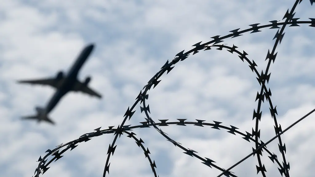 Ein-Flugzeug-startet-hinter-einem-Zaun-mit-Natodraht