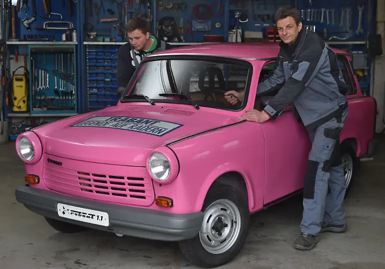 In-der-Werkstatt-des-August-Horch-Museums-in-Zwickau-Sachsen-schieben-Tino-Heimann-r-und-Marvin-Domsch-am-27-04-2016-den-letzten-produzierten-Trabant-in-Position-bevor-er-am-Wochenende-30-04-01-05-im-Museum-gezeigt-wird-Vor-25-Jahren-am-30-April-1991-rollte-der-1-1er-mit-Viertakt-Lizenzmotor-von-Volkswagen-und-40-PS-vom-Band-direkt-ins-Zwickauer-Automobilmuseum-Damit-endete-die-33-jaehrige-Produktion-des-Kleinwagens-Der-pinkfarbene-Flitzer-steht-derzeit-im-Depot-und-ist-nur-zu-besonderen-Anlaessen-zu-sehen