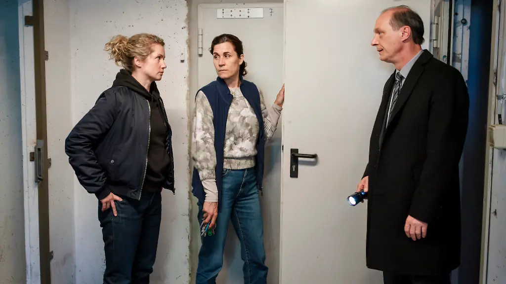 ARD-MDR-TATORT-NACHTSCHATTEN-am-Donnerstag-01-01-26-um-20-15-Uhr-im-ERSTEN-Leonie-Winkler-Cornelia-Groeschel-li-und-Peter-Schnabel-Martin-Brambach-re-bekommen-von-Hausmeisterin-Nina-Kunzendorf-den-Keller-eines-Wohnhauses-gezeigt-MDR-MadeFor-Steffen-Junghans-honorarfrei-Verwendung-gemaess-der-AGB-im-engen-inhaltlichen-redaktionellen-Zusammenhang-mit-genannter-MDR-Sendung-bei-Nennung-Bild-MDR-MadeFor-Steffen-Junghans-S2