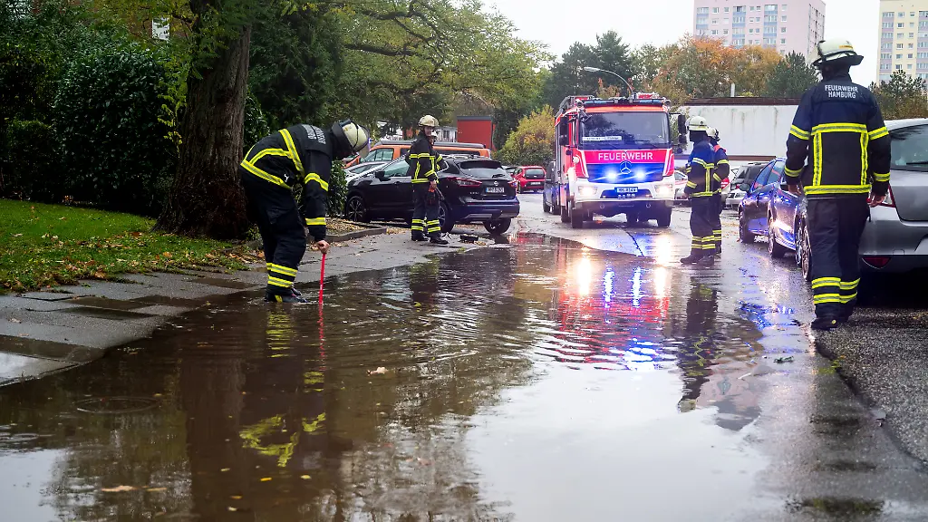 Feuerwehrleute-stehen-im-Stadtteil-Lohbruegge-an-einer-ueberschwemmten-Strasse-Starkregen-hat-am-Nachmittag-in-der-Hansestadt-fuer-zahlreiche-wetterbedingte-Einsaetze-gesorgt