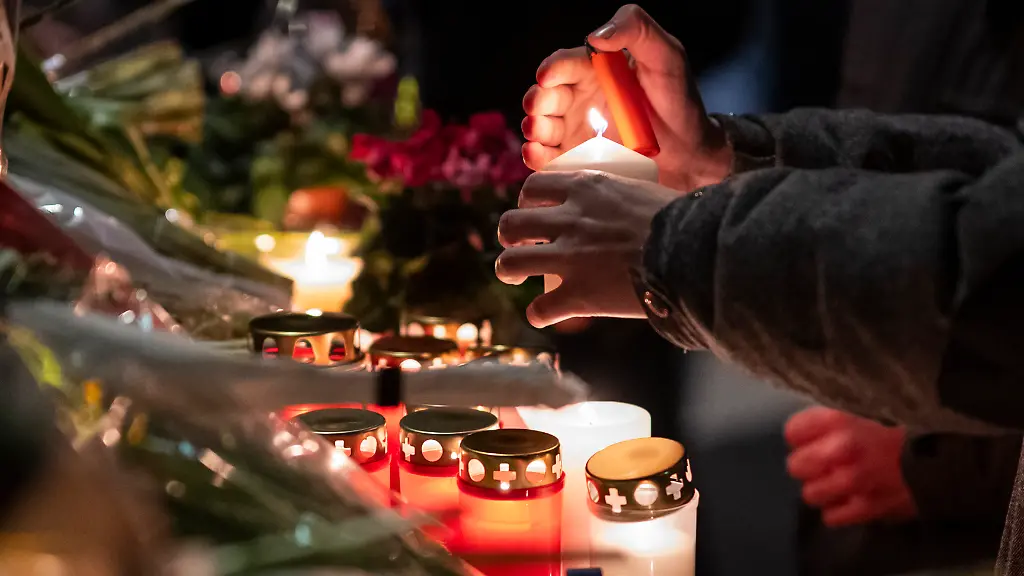 Trauernde-versammeln-sich-um-Blumen-niederzulegen-und-Kerzen-anzuzuenden-um-der-Opfer-des-Brandes-in-der-Bar-und-Lounge-Le-Constellation-zu-gedenken