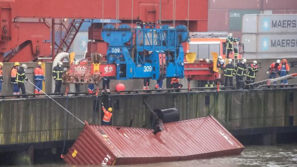 Ein-Container-schwimmt-am-Eurogate-hinter-dem-Containerschiff-Delphis-Gdansk-im-Wasser-und-wird-mit-Hilfe-eines-Krans-gesichert