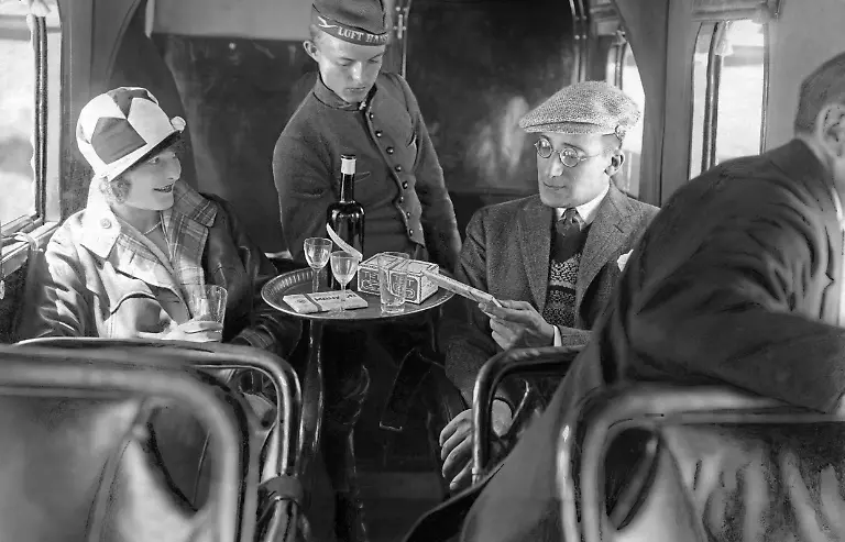 Ein-Steward-der-Lufthansa-serviert-Fluggaesten-Schokolade-und-Schnaps-zu-dieser-Zeit-beschaeftigte-die-Lufthansa-nur-maennliches-Personal-in-den-Kabinen-Aufnahmedatum-01-01-1926-31-12