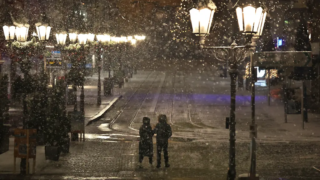 Ein-Paar-laeuft-am-fruehen-Morgen-im-Schneetreiben-durch-die-Innenstadt