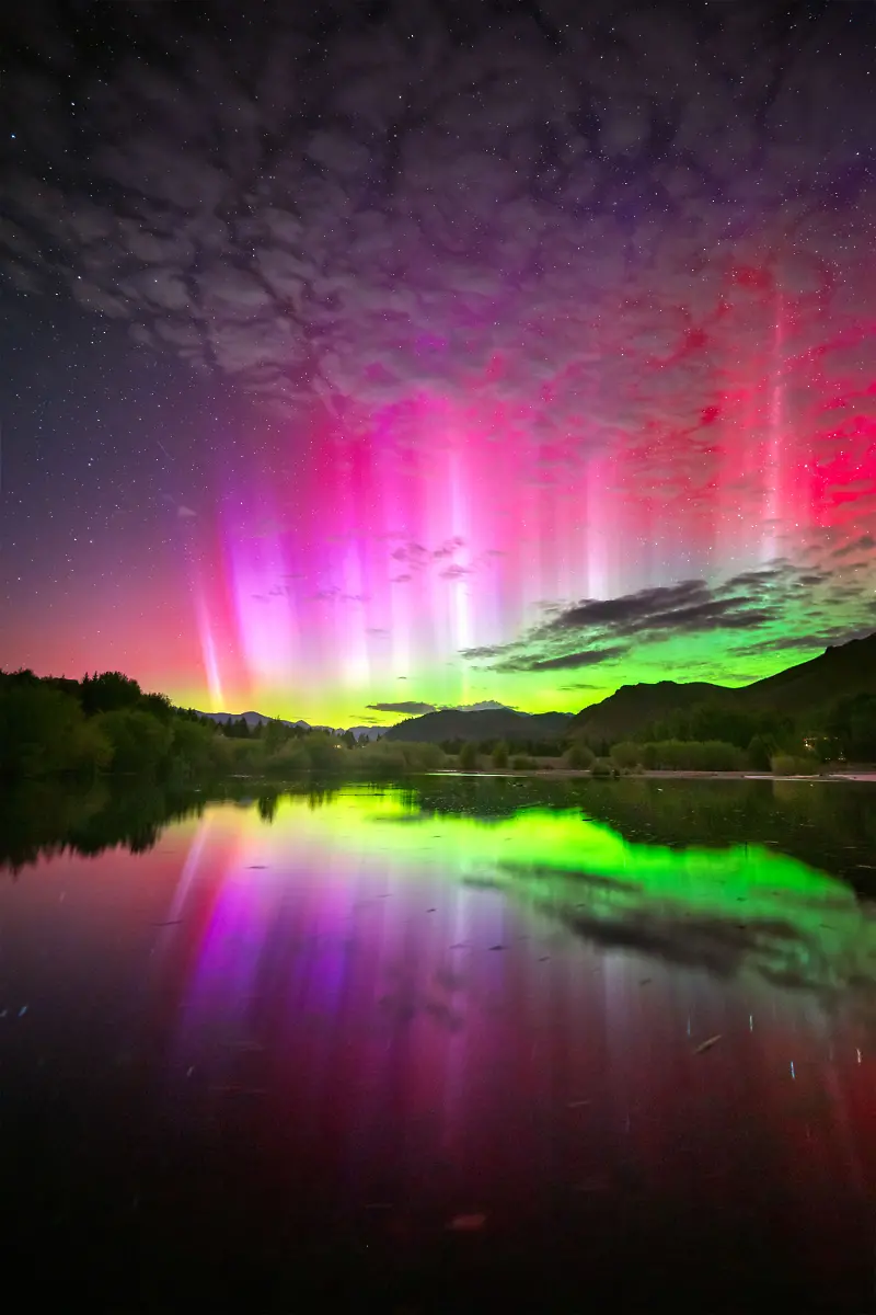 The-night-commenced-with-the-eagerly-anticipated-arrival-of-a-large-coronal-mass-ejection-CME-destined-to-impact-Earth-CMEs-a-primary-cause-of-significant-aurora-displays-serve-as-an-excellent-catalyst-for-the-aurora-to-be-observed-in-lower-latitudes-particularly-during-substorms-which-are-brief-bursts-of-heightened-auroral-activity-The-notification-of-a-CME-impact-came-ringing-in-much-earlier-than-expected-from-SpaceWeatherLive-I-was-well-prepared-and-quickly-headed-out-to-a-secluded-pond-just-north-of-Ketchum-Idaho-After-the-initial-impact-time-seemed-to-slow-down-and-only-a-faint-auroral-glow-was-present-on-the-horizon-I-was-ready-to-throw-in-the-towel-when-suddenly-there-was-an-explosion-of-color-and-the-brightest-naked-eye-red-flares-I-ve-ever-seen-I-ran-down-to-the-pond-to-get-this-particular-shot-of-the-vibrant-red-flares-intertwined-with-the-colors-of-the-aurora-reflecting-off-the-tranquil-pond-Within-minutes-the-substorm-subsided-and-the-aurora-once-again-receded-to-just-a-glow-on-the-horizon-The-aurora-demands-patience-and-meticulous-planning-but-it-s-worth-it-for-those-fleeting-moments-of-awe