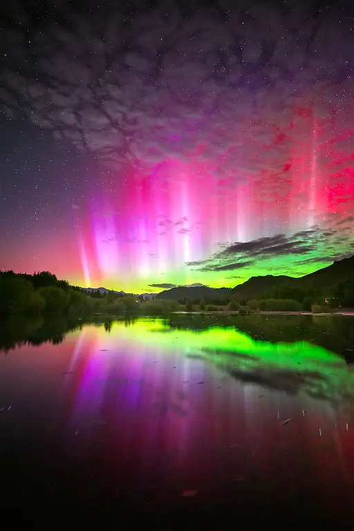 The-night-commenced-with-the-eagerly-anticipated-arrival-of-a-large-coronal-mass-ejection-CME-destined-to-impact-Earth-CMEs-a-primary-cause-of-significant-aurora-displays-serve-as-an-excellent-catalyst-for-the-aurora-to-be-observed-in-lower-latitudes-particularly-during-substorms-which-are-brief-bursts-of-heightened-auroral-activity-The-notification-of-a-CME-impact-came-ringing-in-much-earlier-than-expected-from-SpaceWeatherLive-I-was-well-prepared-and-quickly-headed-out-to-a-secluded-pond-just-north-of-Ketchum-Idaho-After-the-initial-impact-time-seemed-to-slow-down-and-only-a-faint-auroral-glow-was-present-on-the-horizon-I-was-ready-to-throw-in-the-towel-when-suddenly-there-was-an-explosion-of-color-and-the-brightest-naked-eye-red-flares-I-ve-ever-seen-I-ran-down-to-the-pond-to-get-this-particular-shot-of-the-vibrant-red-flares-intertwined-with-the-colors-of-the-aurora-reflecting-off-the-tranquil-pond-Within-minutes-the-substorm-subsided-and-the-aurora-once-again-receded-to-just-a-glow-on-the-horizon-The-aurora-demands-patience-and-meticulous-planning-but-it-s-worth-it-for-those-fleeting-moments-of-awe