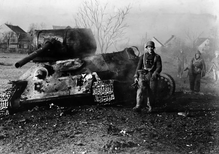 Deutsche-Soldaten-marschieren-an-einem-zerstoerten-sowjetischen-T-34-85-vorbei-Der-Panzer-wurde-nach-einem-Durchbruchsversuch-in-Oberschlesien-zerstoert-Bei-den-Soldaten-handelt-es-sich-hoechstwahrscheinlich-um-Angehoerige-des-Bahnschutzes-der-Reichsbahn-schwarzer-Kragenspiegel-kein-Hoheitsabzeichen-an-der-Uniform