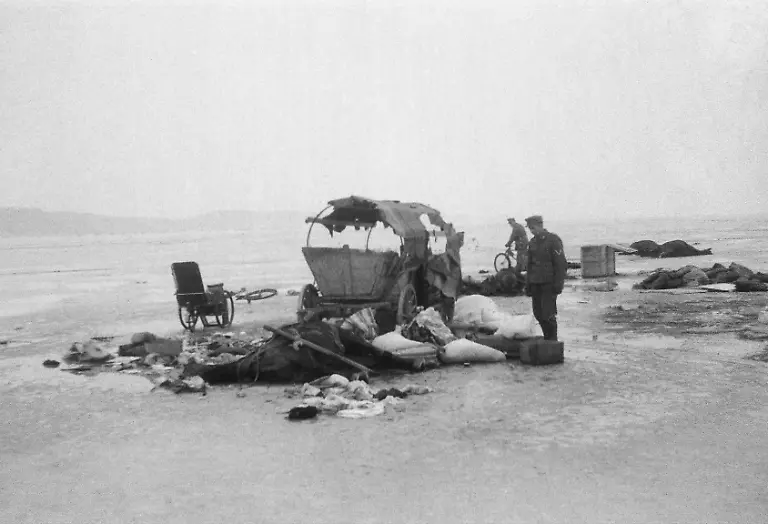 Soldaten-an-einem-durch-Fliegerangriffe-zerstoerten-Wagen-auf-der-Eisflaeche-des-Frischen-Haffs-Anfang-Februar-1945-versuchen-Fluechtlinge-ueber-das-Eis-des-Frischen-Haffs-auf-die-Frische-Nehrung-zu-fliehen-um-entlang-der-Ostseekueste-Danzig-zu-erreichen-Die-Aufnahme-stammt-von-Theodor-Vonolfen-als-Soldat-einer-Luftwaffeneinheit-damals-dort-eingesetzt-Aufnahmedatum-01-02-1945-28-02