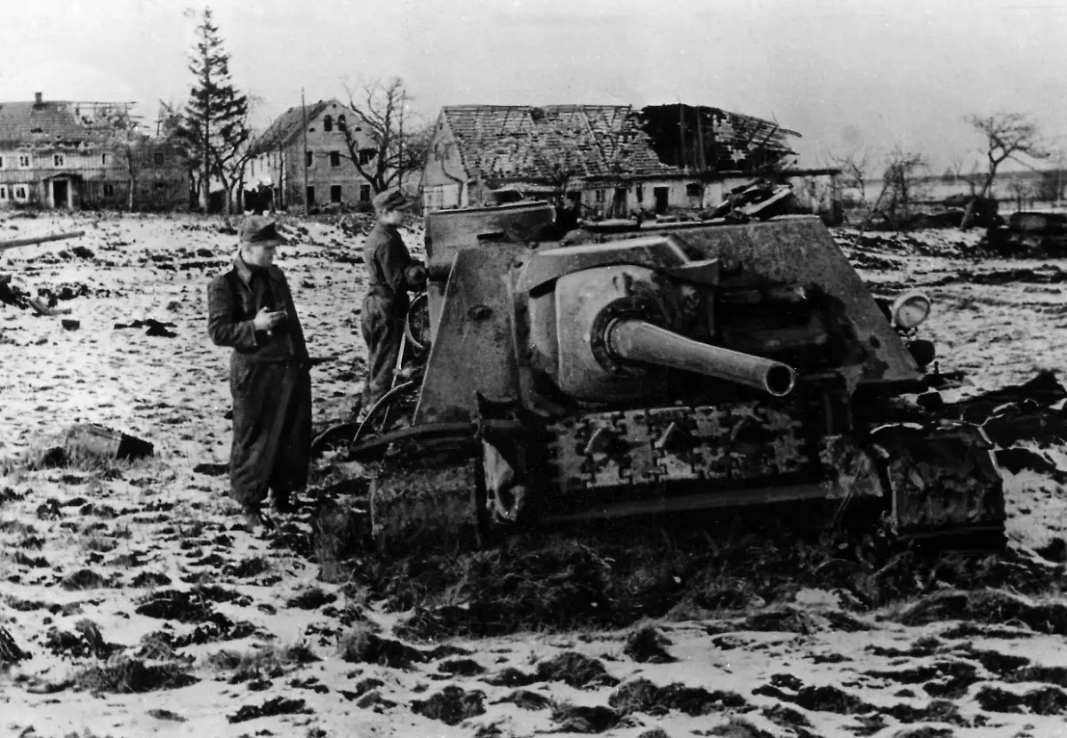 Zwei-deutsche-Soldaten-begutachten-abgeschossene-russische-panzer-Bei-dem-fahrzeug-am-linken-Bildrand-und-in-der-Mitte-handelt-es-sich-um-Jagdpanzer-vom-Typ-SU-100-rechts-im-Hintergrund-sind-zerstoerte-T-34-85-zu-erkennen-Laut-Bildbeschreibung-wurden-die-Panzer-von-Flugzeugen-der-Luftwaffe-vernichtet