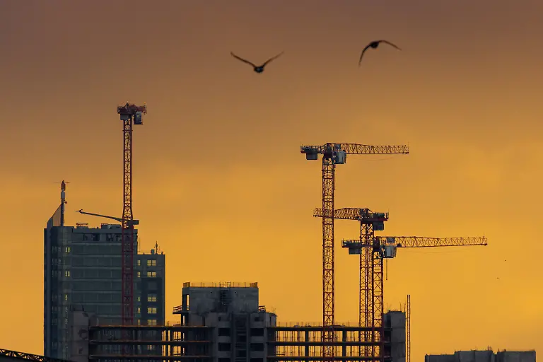 Im-Gegenlicht-der-aufgehenden-Sonne-zeichnen-sich-beim-Blick-von-der-Floesserbuecke-in-Frankfurt-am-Main-die-Hochhaeuser-und-Baukraene-der-Grossbaustelle-am-Kaiserleikreisel-in-Offenbach-am-Main-ab