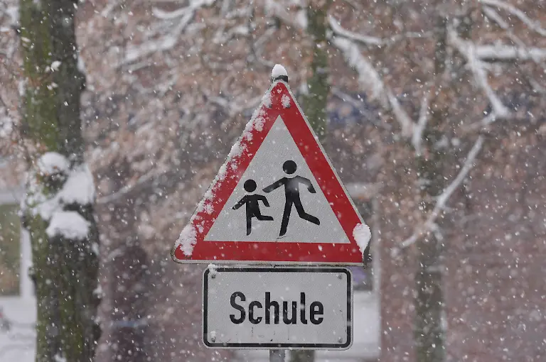 Schnee-liegt-auf-einem-Verkehrsschild-und-Hinweisschild-mit-der-Aufschrift-Schule-vor-einer-Schule-im-Stadtteil-St-Georg-Die-Schulen-in-Hamburg-bleiben-wegen-der-Witterungsverhaeltnisse-und-des-erwarteten-starken-Schneefalls-am-Freitag-geschlossen-Das-teilte-die-Schulbehoerde-mit
