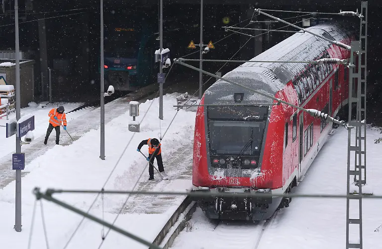 Mitarbeiter-beseitigen-die-zentimeterdicke-Schneeschicht-auf-den-Bahnsteigen-im-Hamburger-Hauptbahnhof