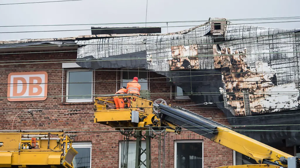 Zwei-Mitarbeiter-der-Deutschen-Bahn-stehen-am-19-01-2018-in-Muenster-Nordrhein-Westfalen-auf-einem-Hubwagon-und-beginnen-mit-den-Aufraeumarbeiten-am-alten-Bahnhofsgebaeude-am-Hauptbahnhof-in-Muenster-Das-Sturmtief-Friederike-hob-am-Vortag-Teile-des-Daches-vom-Gebaeude-ab