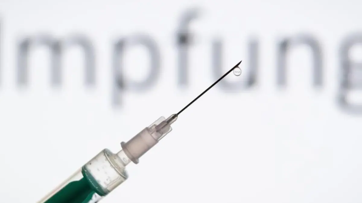 Eine-Spritze-wird-vor-den-Schriftzug-Impfung-gehalten