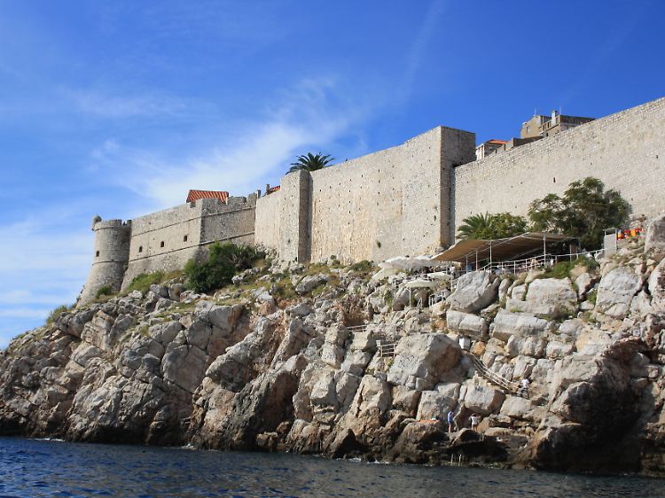 Vor den wuchtigen Festungsmauern von Dubrovnik hat sich eine Bar in die Klippen gekrallt.