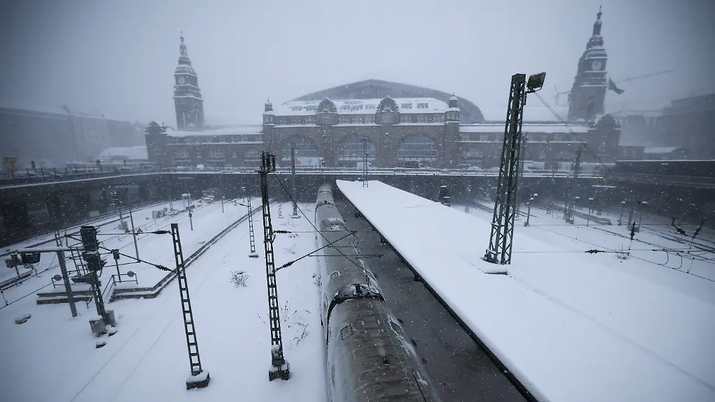 Ein-abgestellter-ICE-steht-bei-Schneefall-an-einem-Bahnsteig-auf-dem-Hauptbahnhof-Die-Deutsche-Bahn-hat-wegen-des-stuermischen-Winterwetters-den-Fernverkehr-im-Norden-Deutschlands-bis-mindestens-zum-Mittag-eingestellt