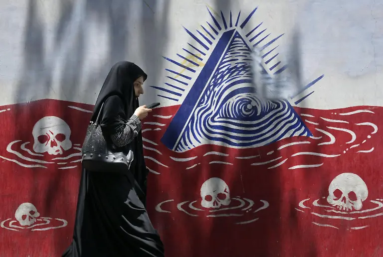 A-woman-in-a-black-chador-walks-past-an-anti-U-S-mural-in-Tehran-on-July-23-2025-about-one-month-after-a-cease-fire-agreement-between-Iran-and-Israel