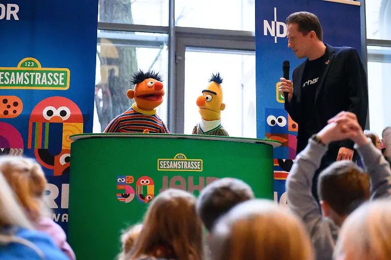 Moderator-Julian-Schlichting-r-befragt-die-Figuren-Ernie-und-Bert-vor-zahlreichen-Kindern-und-Besuchern-Zum-50-jaehrigen-Jubilaeum-der-Sesamstrasse-feiert-das-Museum-fuer-Kunst-und-Gewerbe-MK-G-einen-Aktionstag-fuer-die-ganze-Familie