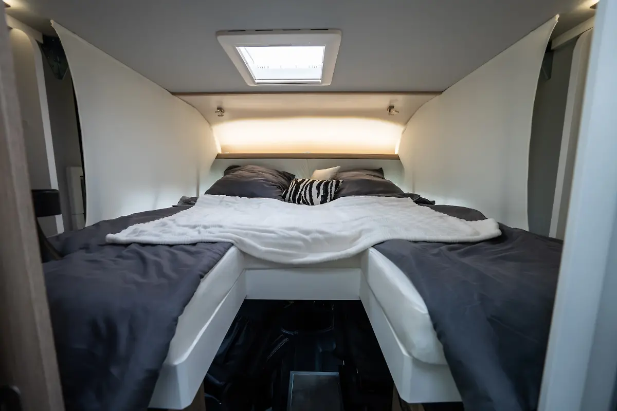 Zudem-bietet-der-I7400-Plus-ein-elektrisch-absenkbares-Hubbett-mit-zwei-laengs-angeordneten-Kojen-ueber-dem-Fahrerhaus