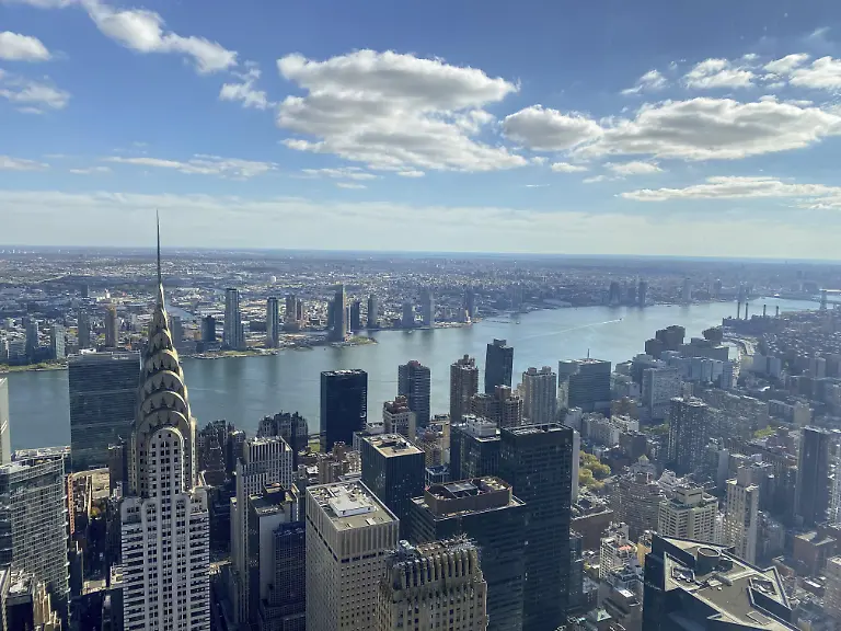 Tagansicht-einer-grossen-Stadt-mit-Blick-auf-den-Fluss-und-zahlreiche-Wolkenkratzer-darunter-das-Chrysler-Building-bei-blauem-Himmel-und-Wolken-new-york-von-oben-mit-beeindruckenden-Wolkenkratzern-und-wolken-am-himmel-New-york-USA-Nordamerika