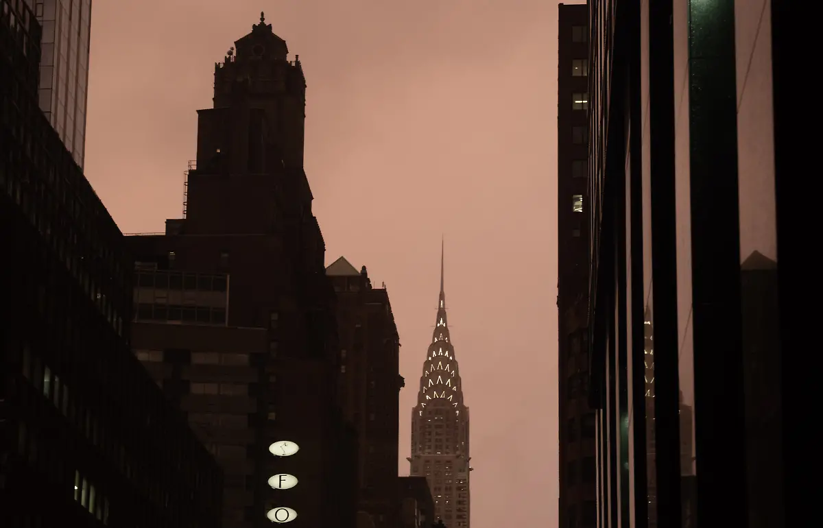 December-3-2025-New-York-New-York-USA-The-Chrysler-Building-stands-among-surrounding-office-buildings-under-a-warm-maroon-hued-glow-along-Lexington-Avenue-during-a-late-afternoon-rain-shower