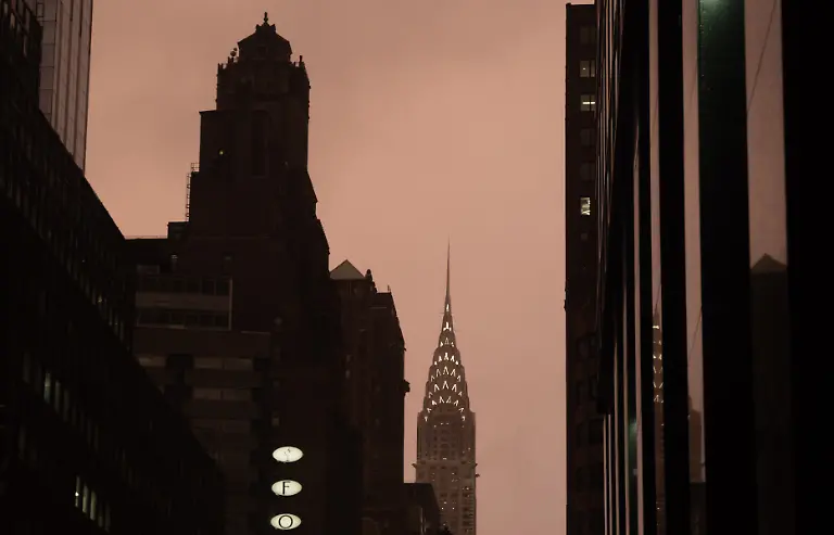 December-3-2025-New-York-New-York-USA-The-Chrysler-Building-stands-among-surrounding-office-buildings-under-a-warm-maroon-hued-glow-along-Lexington-Avenue-during-a-late-afternoon-rain-shower