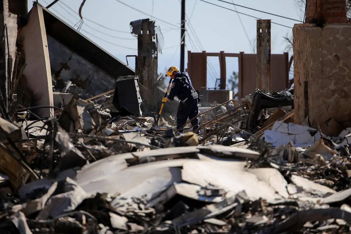 A-search-and-rescue-worker-investigates-the-charred-remains-of-a-house-as-the-Eaton-Fire-continues-in-Altadena-Los-Angeles-County-California-U-S-January-15-2025