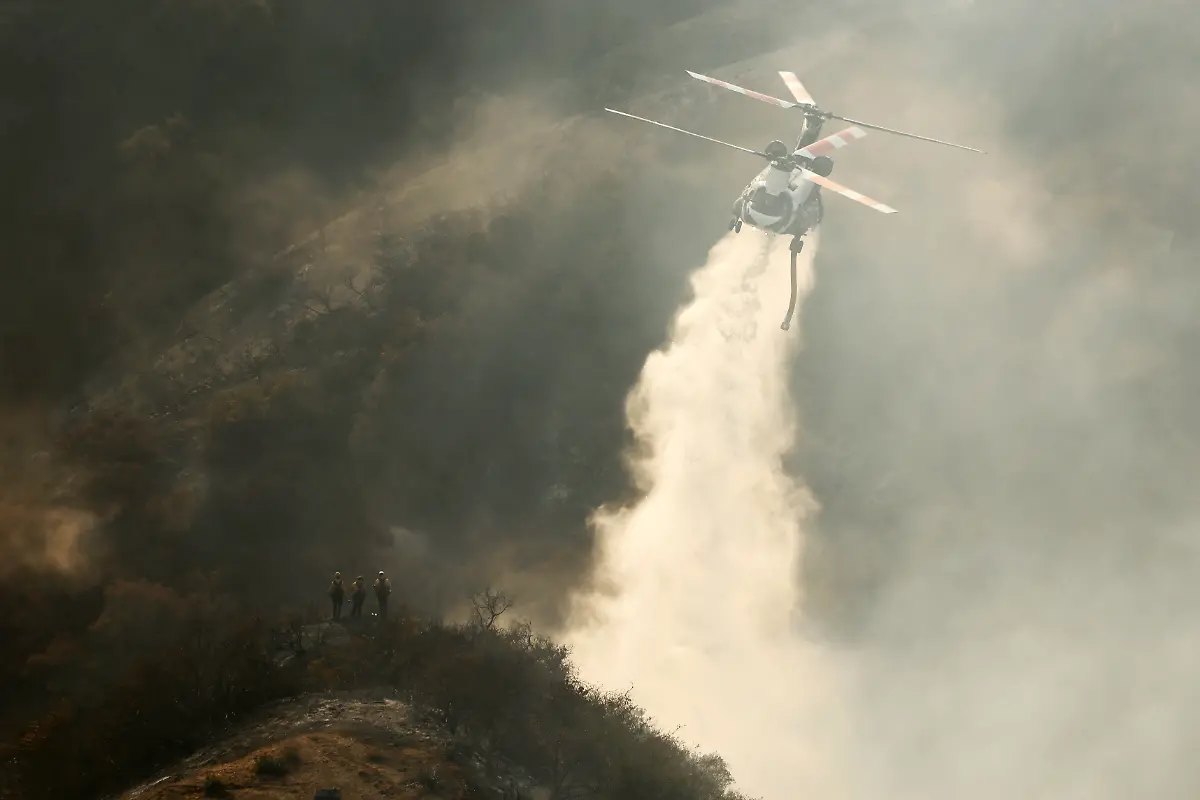 A-helicopter-makes-a-drop-as-smoke-billows-from-the-Palisades-Fire-at-the-Encino-neighbourhood-of-Los-Angeles-California-U-S-January-11-2025