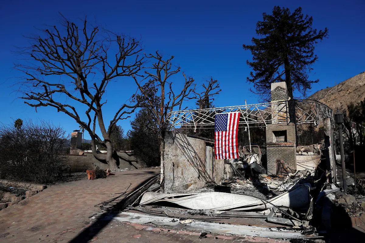 A-U-S-flag-hangs-from-a-damaged-home-as-the-Eaton-Fire-continues-in-Altadena-California-U-S-January-14-2025