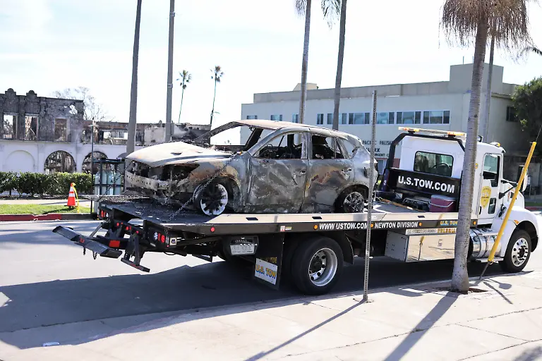 A-flatbed-tow-truck-removes-a-car-which-burned-during-the-Palisades-Fire-on-the-day-U-S-President-Donald-Trump-will-meet-first-responders-in-Pacific-Palisades-Los-Angeles-U-S-January-24-2025