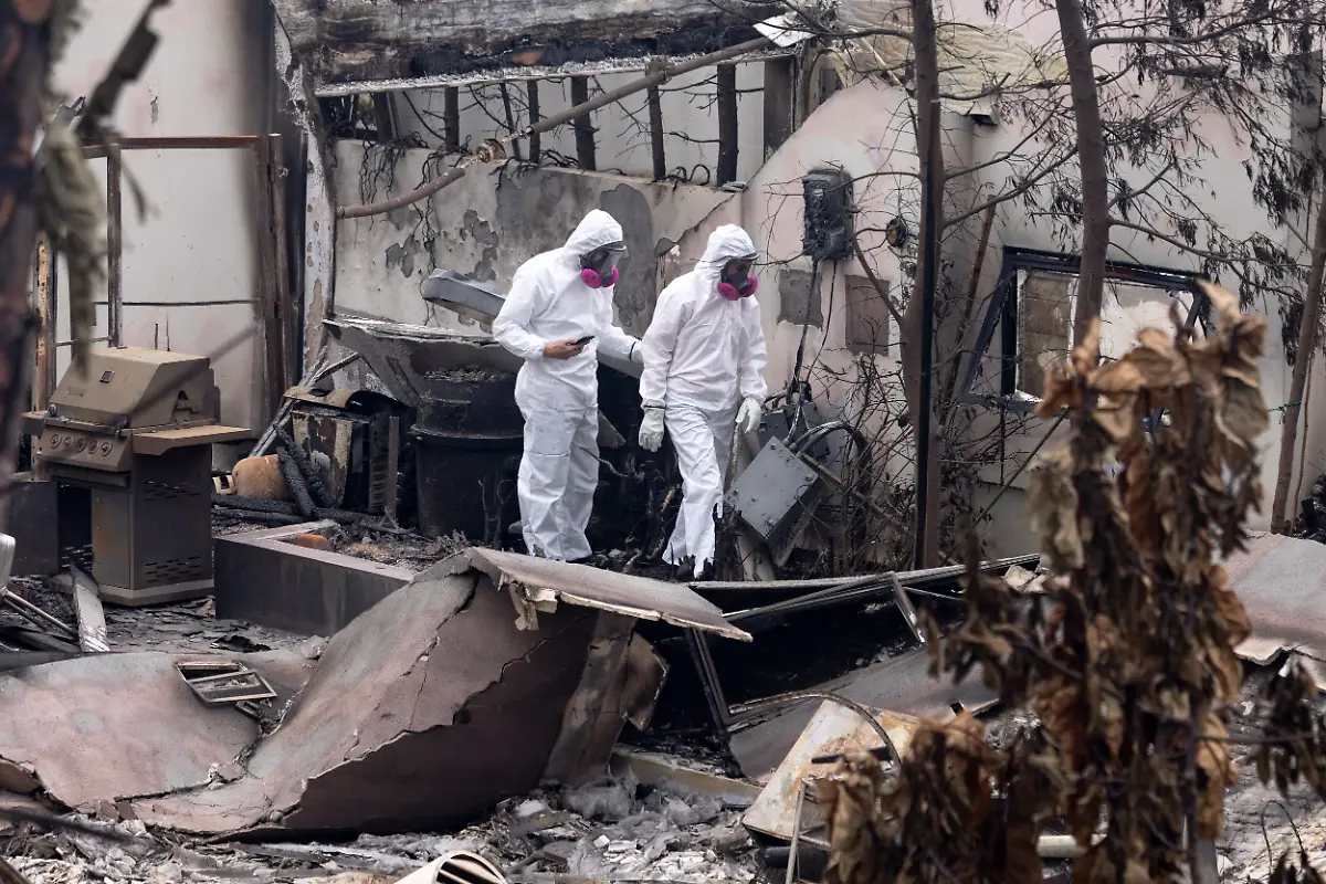 Homeowners-dressed-in-full-body-protective-gear-walk-among-the-rubbles-of-their-house-destroyed-by-the-Palisades-Fire-in-the-Pacific-Palisades-neighborhood-of-Los-Angeles-Calif-Saturday-Jan-25-2025