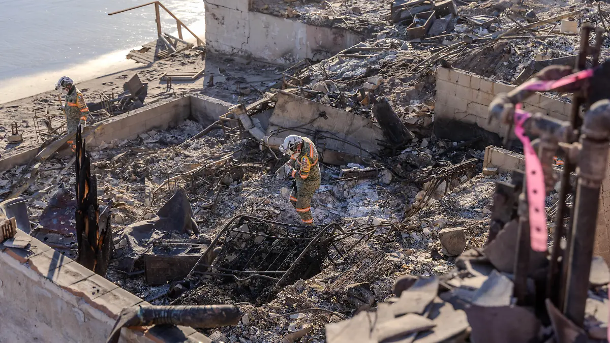 January-15-2025-Pacific-Palisades-California-USA-The-Mexican-military-has-come-to-assist-AmericaA-a-a-s-National-Urban-Search-Rescue-US-R-and-Cal-Fire-to-find-human-remains-in-the-homes-and-businesses-that-burnt-during-the-Palisades-Fire-They-stand-on-a-destroyed-structure-overlooking-the-Pacific-Ocean-lined-with-burnt-palm-trees-along-the-Pacific-Coast-Highway-after-a-long-day-of-sifting-through-toxic-debris