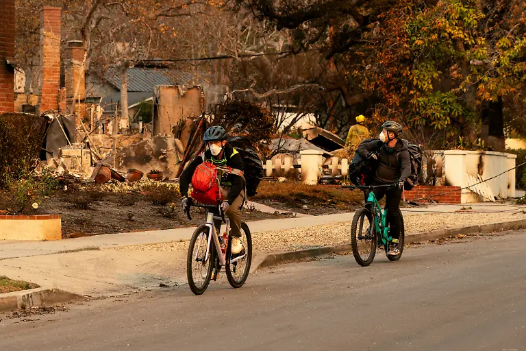 Cyclists-leave-with-full-backpacks-near-homes-that-were-destroyed-by-the-Palisades-Fire-in-the-Pacific-Palisades-neighborhood-in-Los-Angeles-California-U-S-January-11-2025