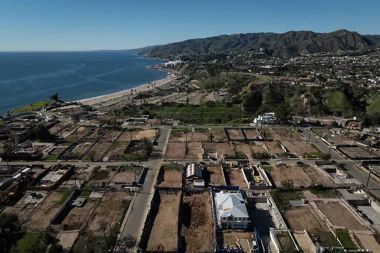 Haeuser-die-wieder-aufgebaut-werden-sind-umgeben-von-geraeumten-Grundstuecken-im-Stadtteil-Pacific-Palisades-in-Los-Angeles-ein-Jahr-nach-dem-Palisades-Feuer