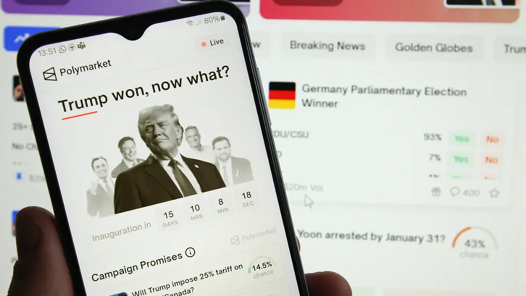 Auf-einem-Smartphone-wurde-die-App-der-Blockchain-basierten-Wettplattform-Polymarket-aufgerufen-Dahinter-wurde-auf-einem-Laptop-die-Website-der-Prognosemarktplattform-mit-der-Prognose-zum-Ausgang-der-Bundestagswahlen-am-23-Februar-aufgerufen-Auf-Polymarket-kann-unter-anderem-auf-den-Sieger-der-Bundestagswahlen-gesetzt-werden-Symbolbild-Symbolfoto