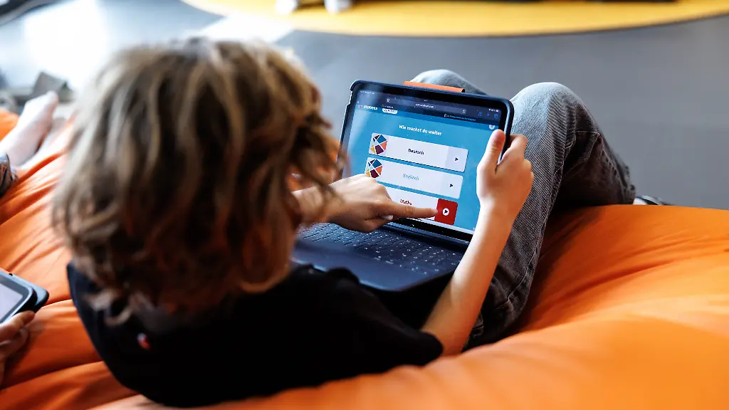 Ein-Schueler-einer-fuenften-Klasse-bedient-in-einem-Study-Raum-an-der-Bischof-Ulrich-Realschule-in-Augsburg-Bayern-ein-Tablet-und-waehlt-das-Schulfach-Mathe-aus-An-der-Schule-wird-nach-den-Schulkonzept-ULI-Unser-Lernen-inspiriert-gearbeitet-wobei-die-Schuelerinnen-und-Schueler-gezielt-in-ihrer-Selbststaendigkeit-in-ihrer-Verantwortung-fuer-das-eigene-Lernen-und-in-ihrer-sozialen-Kompetenz-gefoerdert-werden