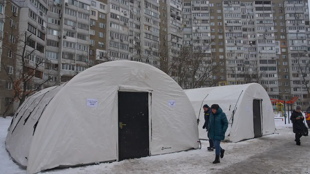 Anwohner-gehen-an-einem-der-Zelte-vorbei-die-der-Katastrophenschutz-nach-den-russischen-Luftangriffen-auf-den-ukrainischen-Energiesektor-aufgestellt-hat-Ein-Teil-der-Bewohner-der-Stadt-sind-mitten-im-Winter-ohne-Strom-Wasser-und-Heizung