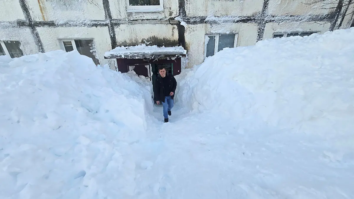 A-man-walks-out-of-an-apartment-block-surrounded-by-snowdrifts-after-an-extreme-snowstorm-hit-the-far-eastern-city-of-Petropavlovsk-Kamchatskiy-Russia-January-17-2026