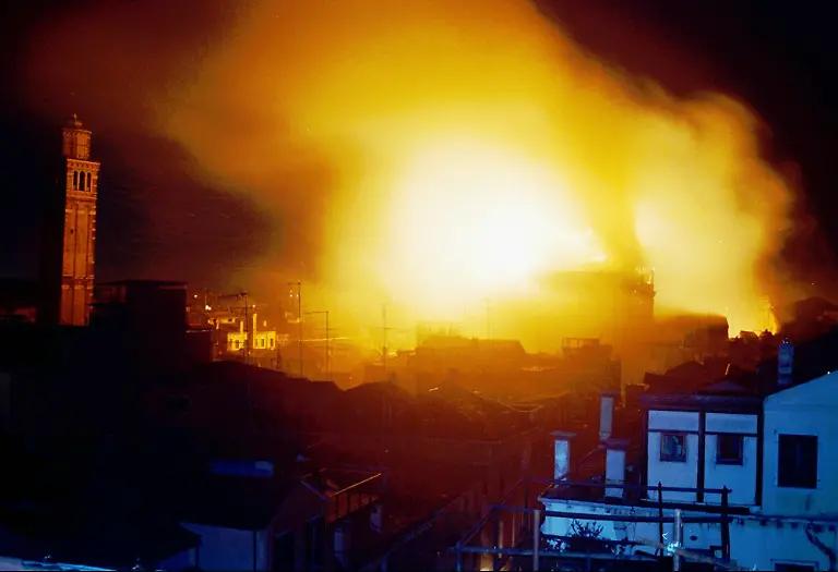 Flames-leap-into-the-sky-from-a-huge-fire-which-destroyed-Venice-s-La-Fenice-Opera-House-Monday-Jan-29-1996-A-204-year-old-jewel-that-was-one-of-Italy-s-greatest-artistic-institutions-La-Fenice-had-been-closed-for-urgent-repairs-and-was-to-reopen-in-March-with-a-performance-of-Don-Giovanni-and-a-jazz-concert-by-Woody-Allen-Tower-at-left-of-photo-is-belltower-of-St-Stefano-church