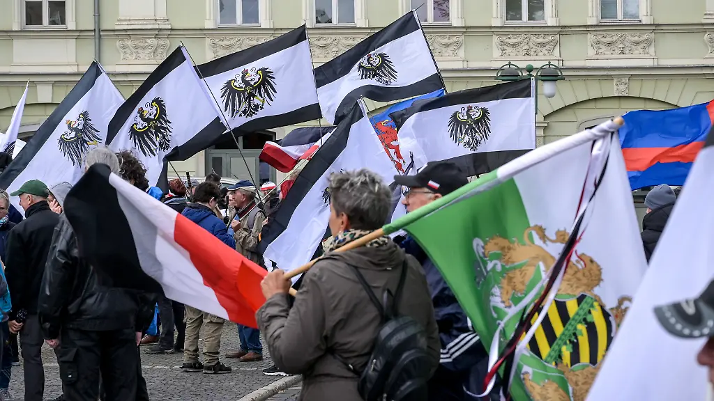Teilnehmer-einer-Versammlung-der-sogenannten-Reichsbuerger-Szene-zeigen-Fahnen-mit-dem-Preussischen-Adler-Auf-dem-Platz-der-Demokratie-kommen-sie-zu-einem-bundesweiten-Treffen-zusammen-und-ziehen-anschliessend-durch-die-Innenstadt