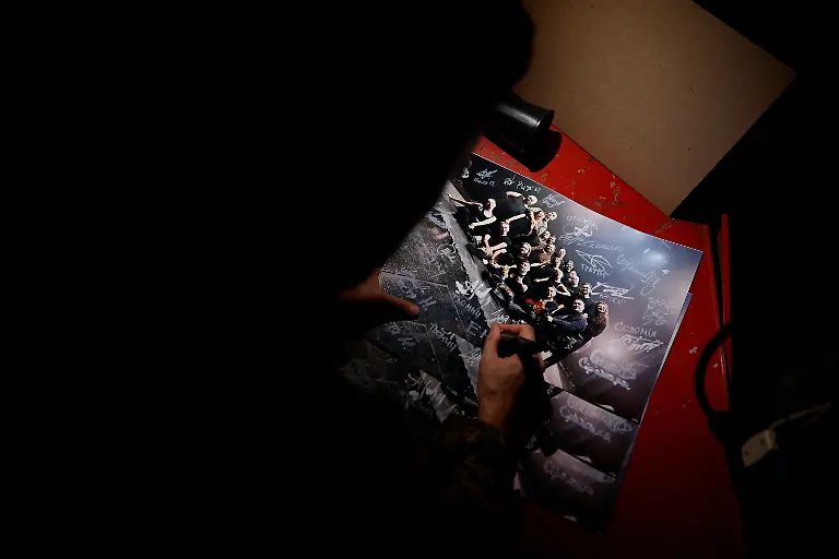 Ivan-Voinov-33-signs-a-picture-of-all-the-members-of-the-Veterans-Theatre-group-before-the-premiere-of-an-18th-century-Ukrainian-parody-of-Virgil-s-Aeneid-amid-Russia-s-attack-on-Ukraine-in-Kyiv-Ukraine-December-4-2025-Fellow-member-and-veterans-psychologist-Yehor-Babenko-27-said-the-transformative-trauma-of-serious-injury-often-compels-people-to-seek-meaning-in-something-new-He-said-it-was-critical-for-his-fellow-comrades-to-understand-that-life-does-not-simply-end-after-a-serious-injury-Sometimes-you-understand-it-s-the-opposite-that-it-just-starts-getting-going-REUTERS-Alina-Smutko-SEARCH-UKRAINE-SMUTKO-THEATRE-FOR-THIS-STORY-SEARCH-WIDER-IMAGE-FOR-ALL-STORIES